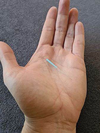 naald in handpalm, beslaat helft van de breedte